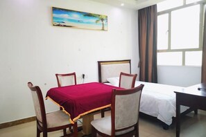 A hotel room with a bed, a desk, a chair, and a table. - Huizhou Qibin Homestay (Huidong)