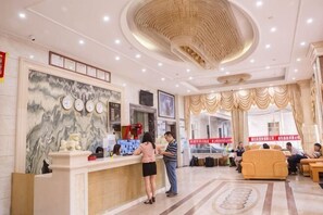 Eine Hotelhalle mit Empfangstresen, einer großen Wand mit Marmoroptik und einer Sitzecke mit Sofas.