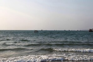 A calm sea with boats in the distance and waves approaching the shore. - Huizhou Qibin Homestay (Huidong)