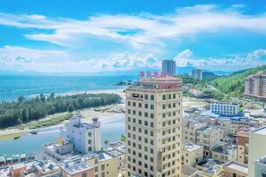 A high-rise building with multiple floors, surrounded by other buildings and a body of water. - Huizhou Qibin Homestay (Huidong)