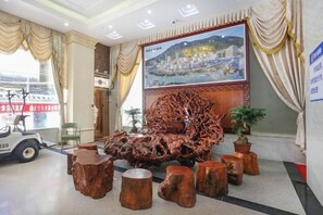 A lobby with a large painting, wooden sculptures, and a view of a cityscape through the window. - Huizhou Qibin Homestay (Huidong)