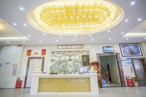 A hotel reception area with a large chandelier, a reception desk, and a wall-mounted television. - Huizhou Qibin Homestay (Huidong)