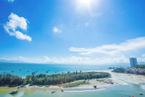 A coastal landscape with a clear sky, a beach, and a forested area. - Huizhou Qibin Homestay (Huidong)