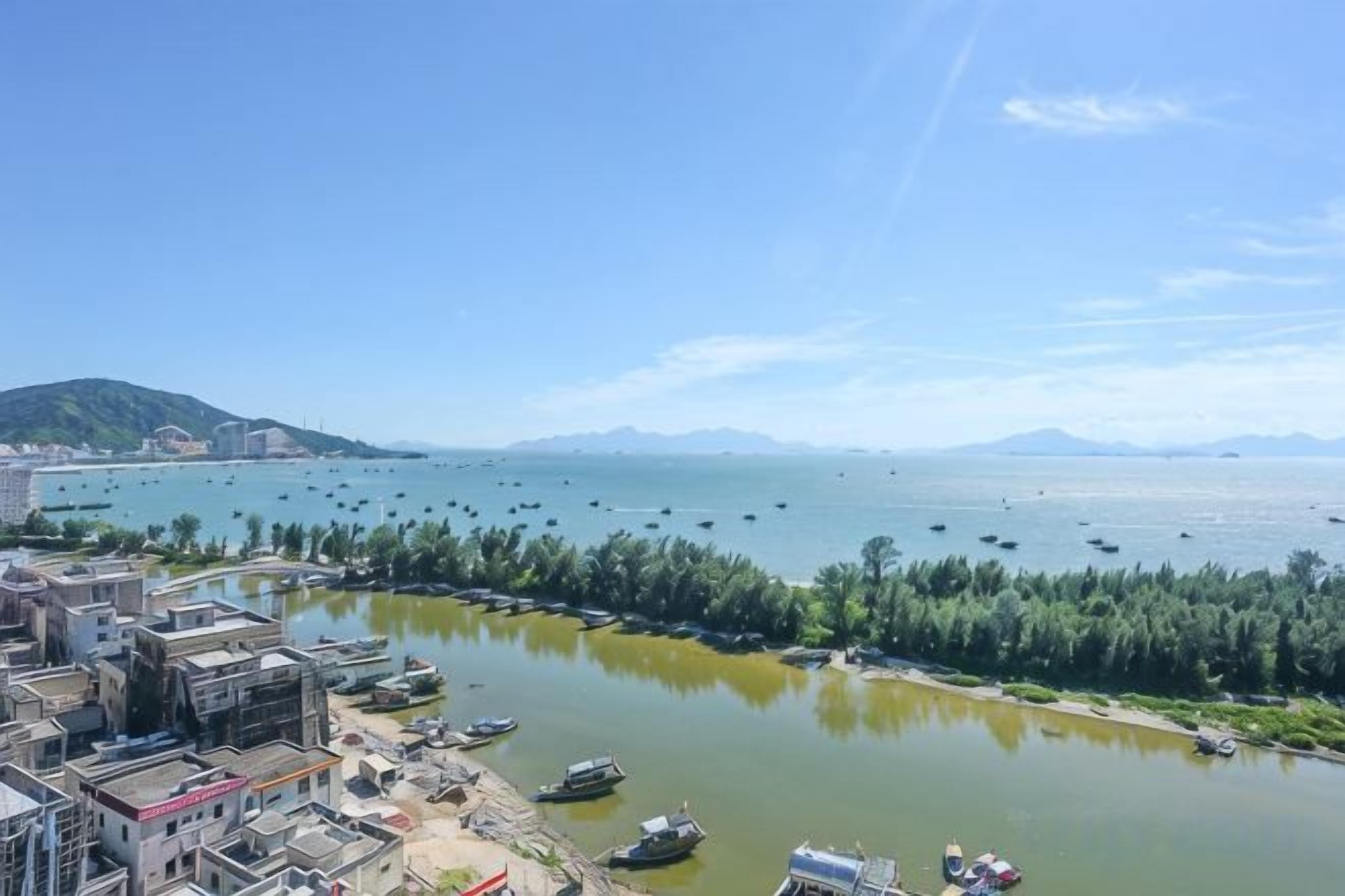 A coastal town with a marina, buildings along the waterfront, and a clear view of the sea.