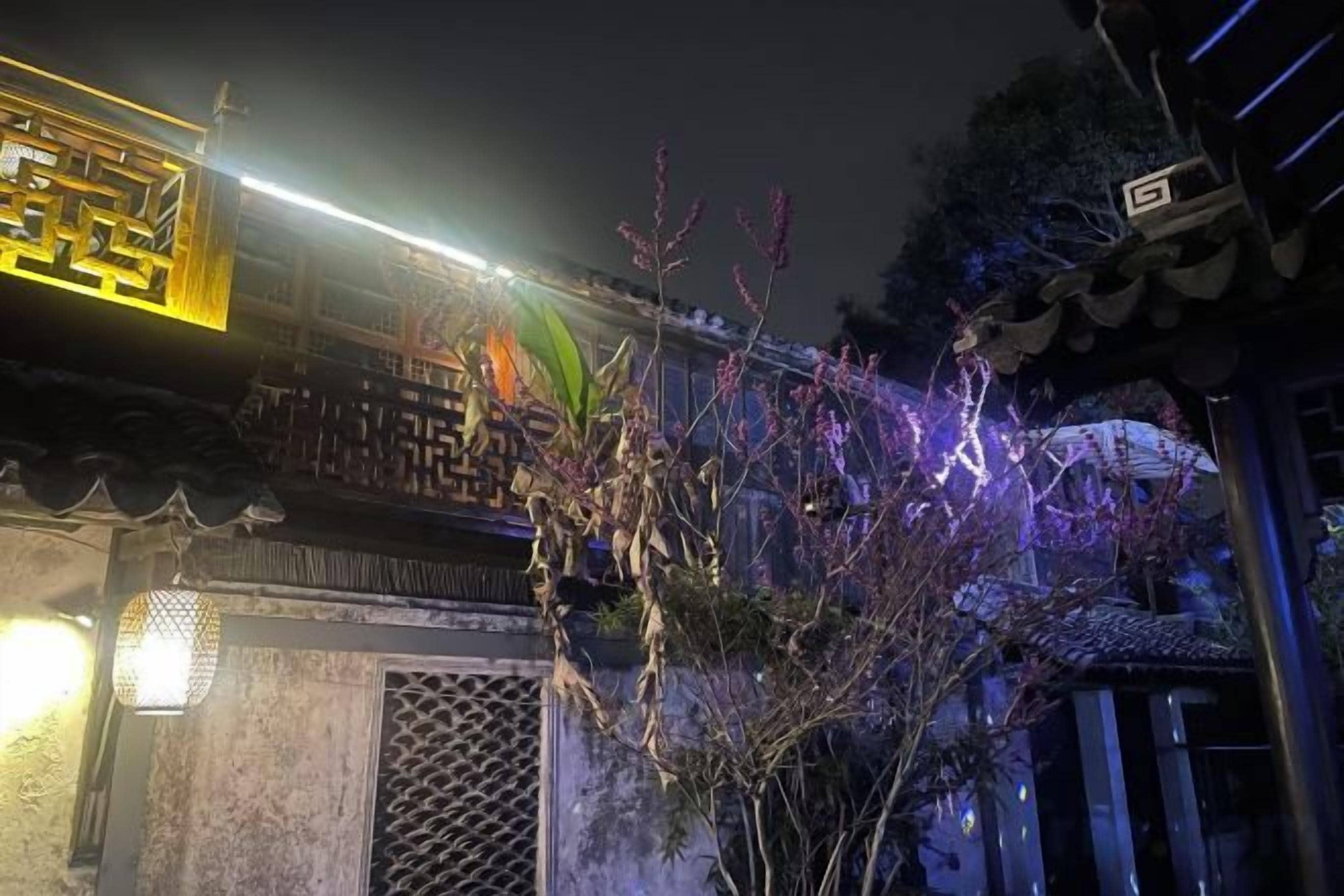 Un edificio tradicional con un acceso decorativo y un camino iluminado.