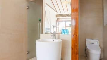 A bathroom with a white sink, a toilet, and a glass shower enclosure.