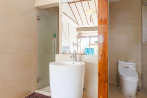 A bathroom with a white sink, a toilet, and a glass shower enclosure. - Pushe Guiyin Inn (Kunshan)