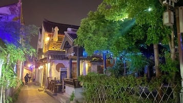A narrow street with traditional architecture, a pedestrian walkway, and a fence.