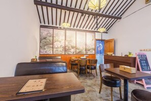 A restaurant interior with wooden furniture, a traditional Japanese sliding door, and a chalkboard menu. - Pushe Guiyin Inn (Kunshan)