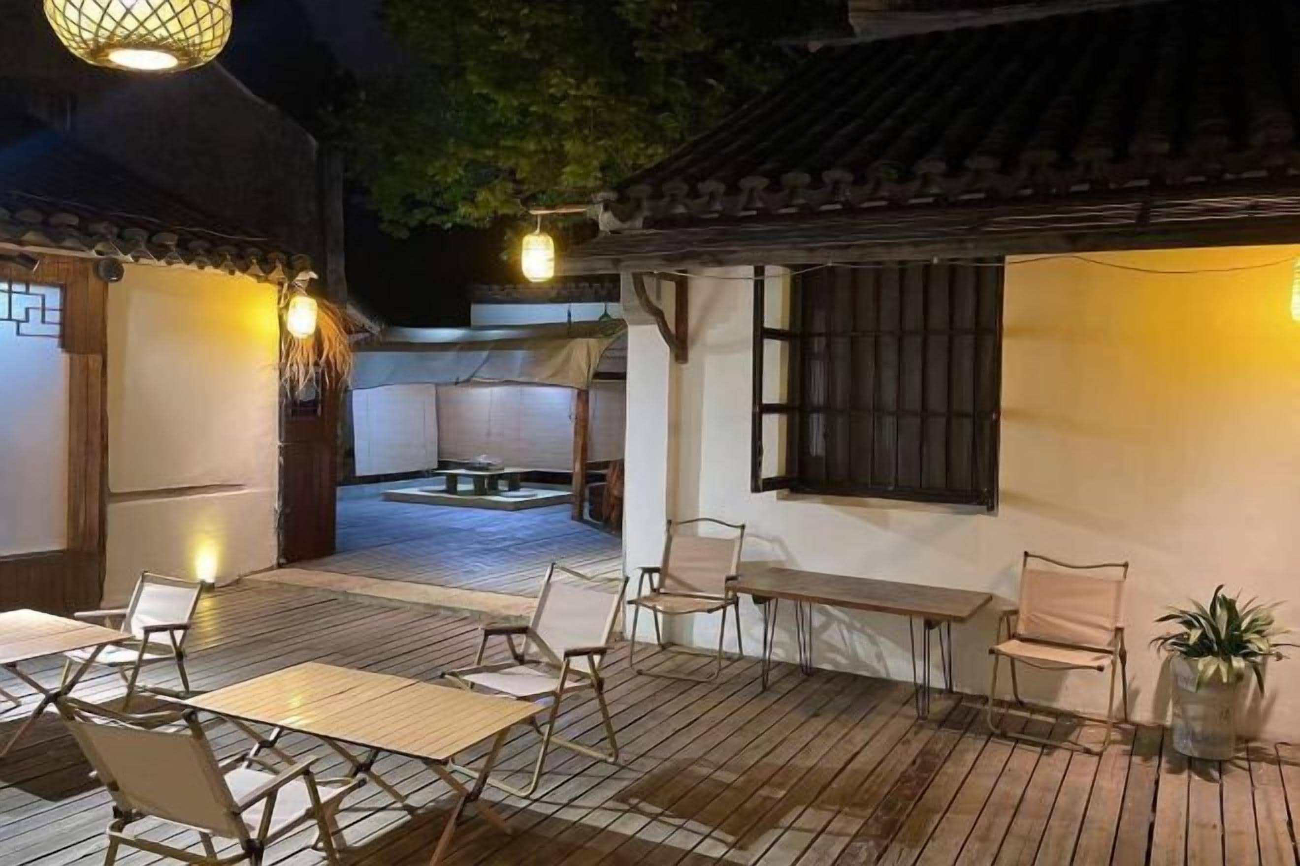 Un patio al aire libre con una mesa, sillas, un rincón de descanso y una pared con una ventana.
