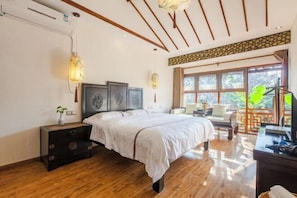 A bedroom with a wooden floor, a bed with a white bedspread, a nightstand with a vase, and a window with a view of greenery. - Pushe Guiyin Inn (Kunshan)