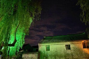 A traditional building with a tiled roof and a single window, surrounded by trees. - Pushe Guiyin Inn (Kunshan)