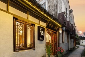 A traditional building with a signboard, wooden window frames, and a pathway leading to the entrance. - Pushe Guiyin Inn (Kunshan)