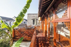 A traditional wooden balcony with a lattice design, a hanging lantern, and a view of the surrounding buildings. - Pushe Guiyin Inn (Kunshan)