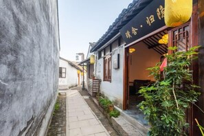 Een smalle steeg met traditionele architectuur, waaronder een gebouw met een pannendak en houten deuren.