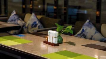 Una habitación de hotel con una mesa ordenada, un florero con planta y un candelabro decorativo.