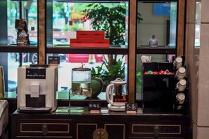 Un coin café équipé d’une machine à café, d’une bouilloire et d’un porte-tasses.