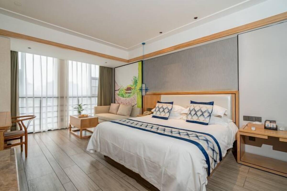Een moderne hotelkamer met een groot bed, een zithoek en een bureau.