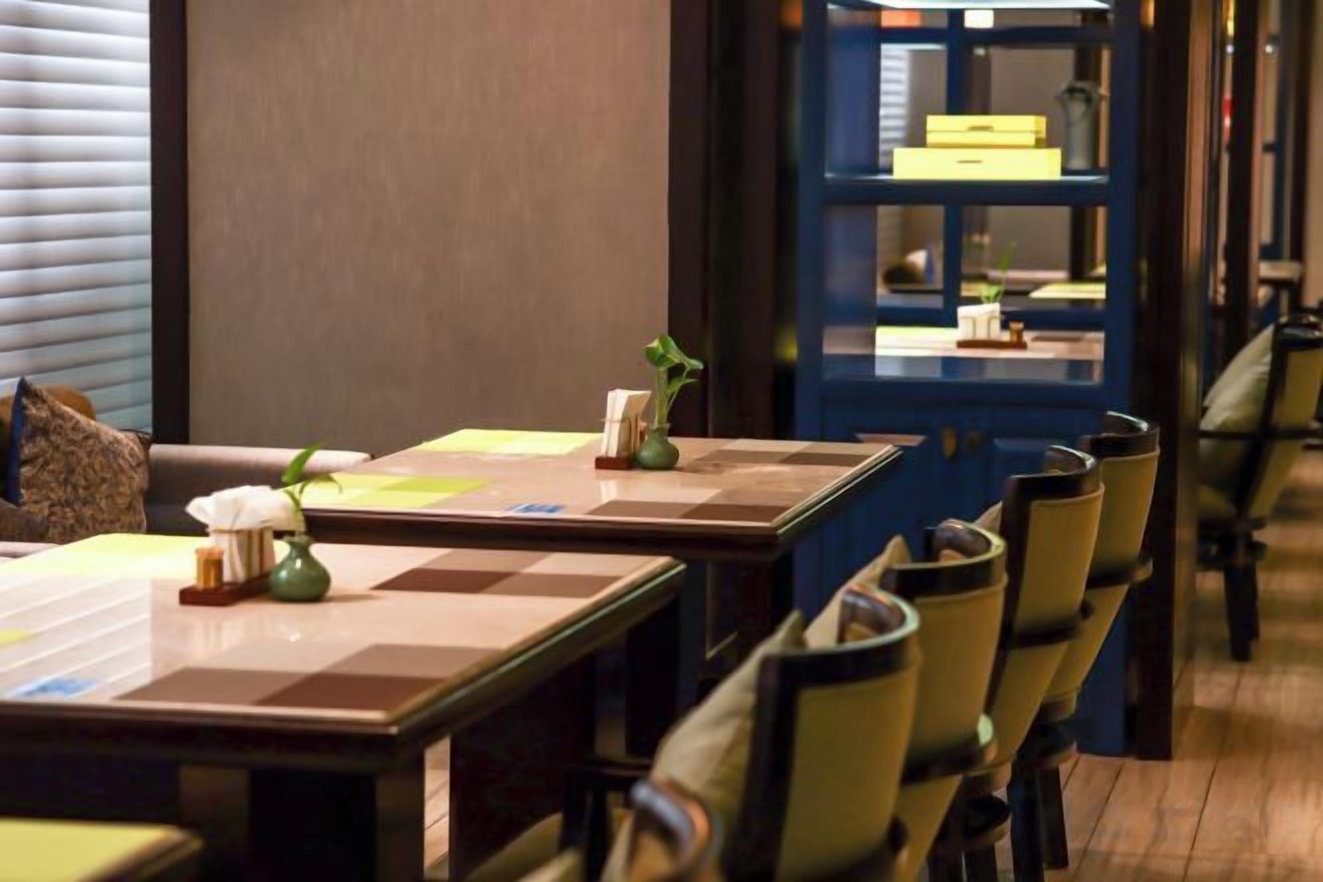 A restaurant interior with tables and chairs, a blue counter, and a wall-mounted display case.