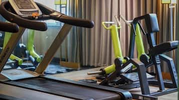 Un gimnasio con equipamiento de ejercicio, incluyendo una cinta de correr y máquinas de pesas.