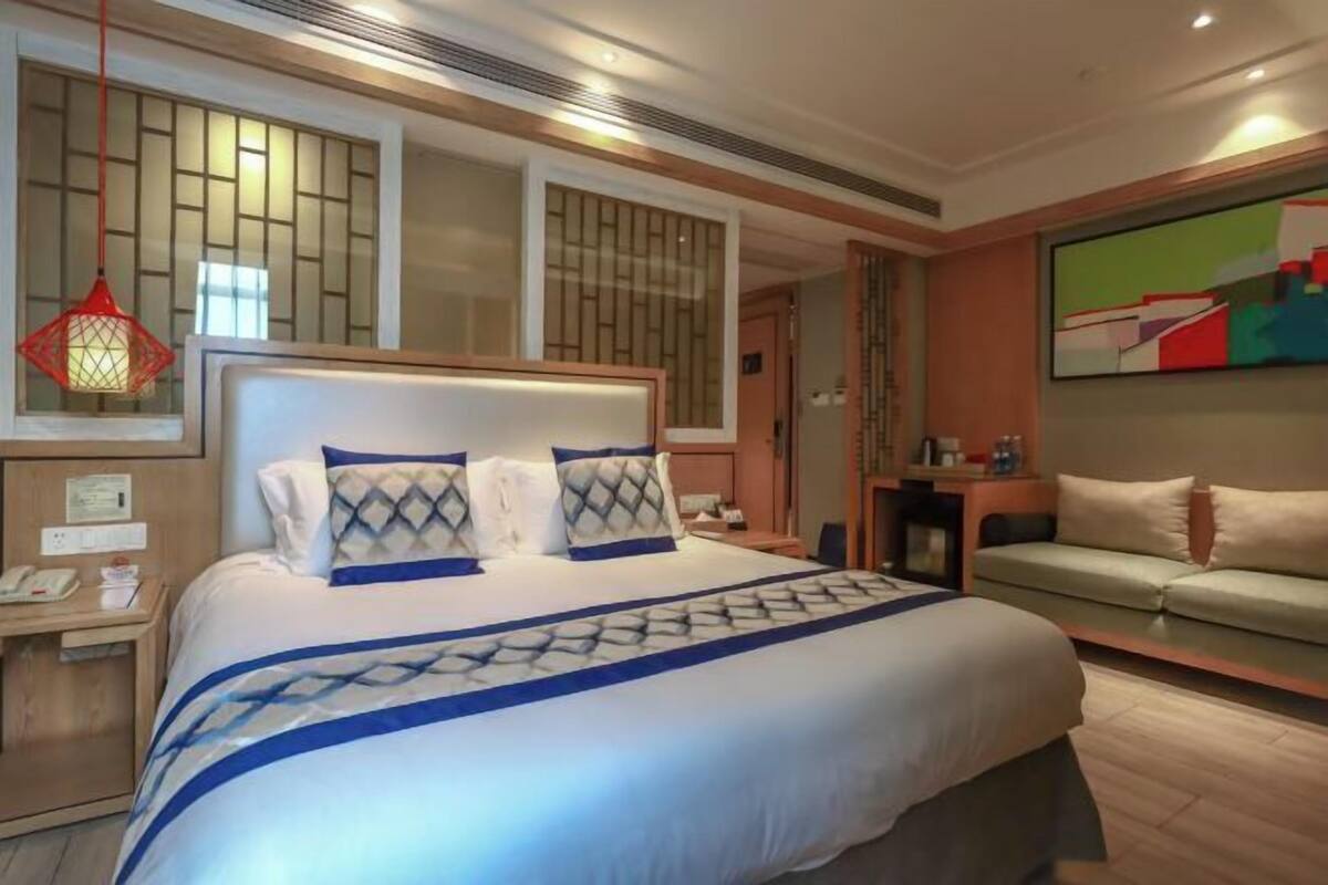 Een hotelkamer met een groot bed, een nachtkastje, een bank en een schilderij aan de muur.