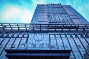 Un edificio alto con fachada de vidrio moderna y un logotipo circular en la base.