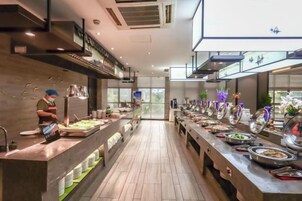 Montaje tipo buffet con varias estaciones de comida y una larga barra.