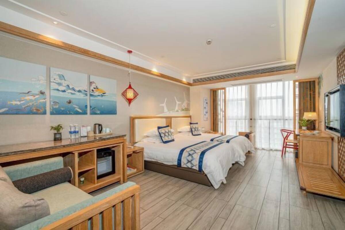 Een hotelkamer met een bed, een bureau, een televisie en kunst aan de muur.