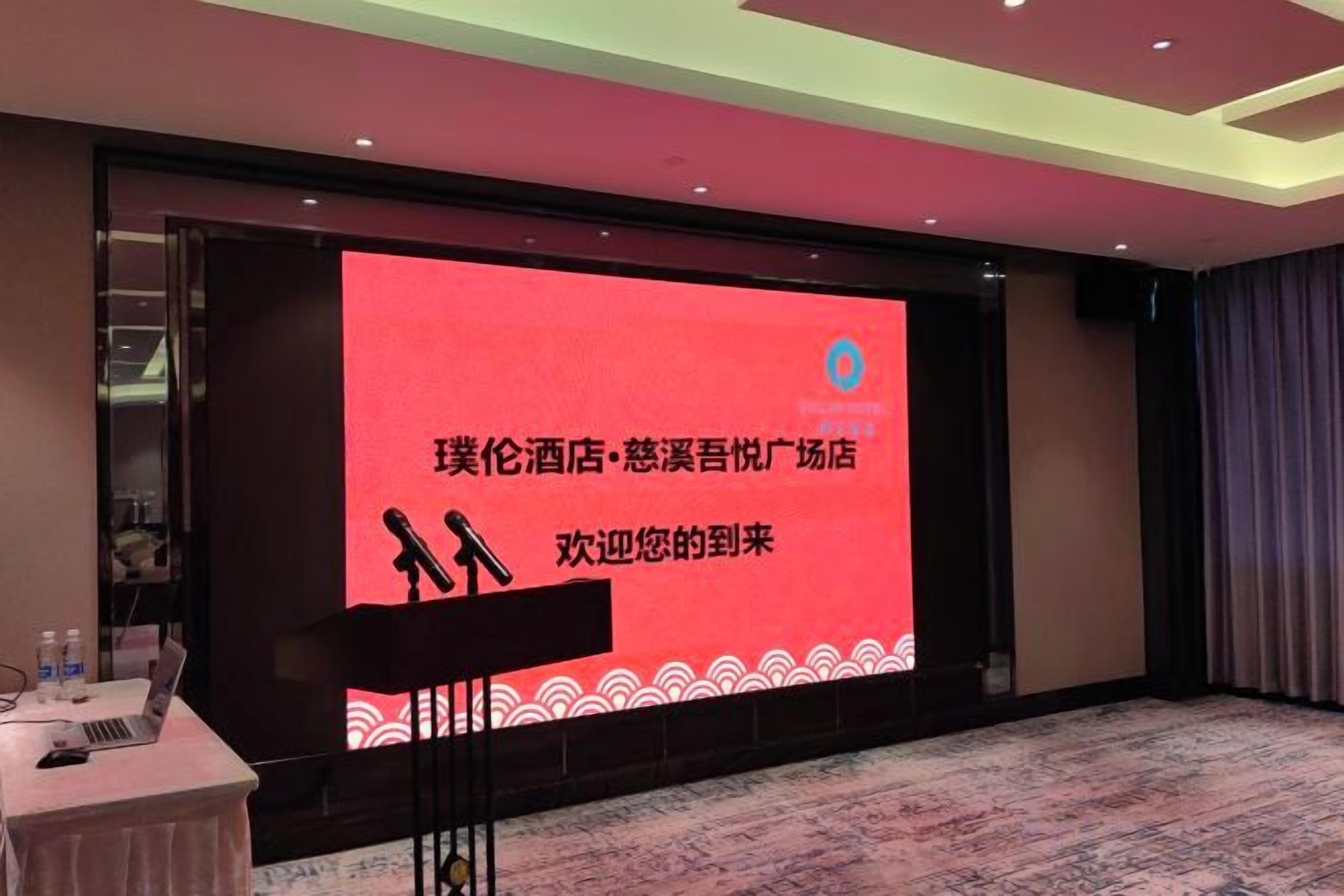 A conference room with a large screen displaying text, a podium, and a carpeted floor.