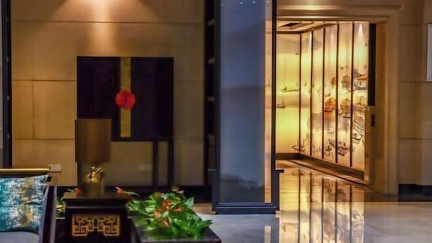 A modern lobby with a polished floor, a reception desk, and a decorative wall with a red flower. - PULUN HoTEL (Cixi Wuyue Plaza) (Cixi)