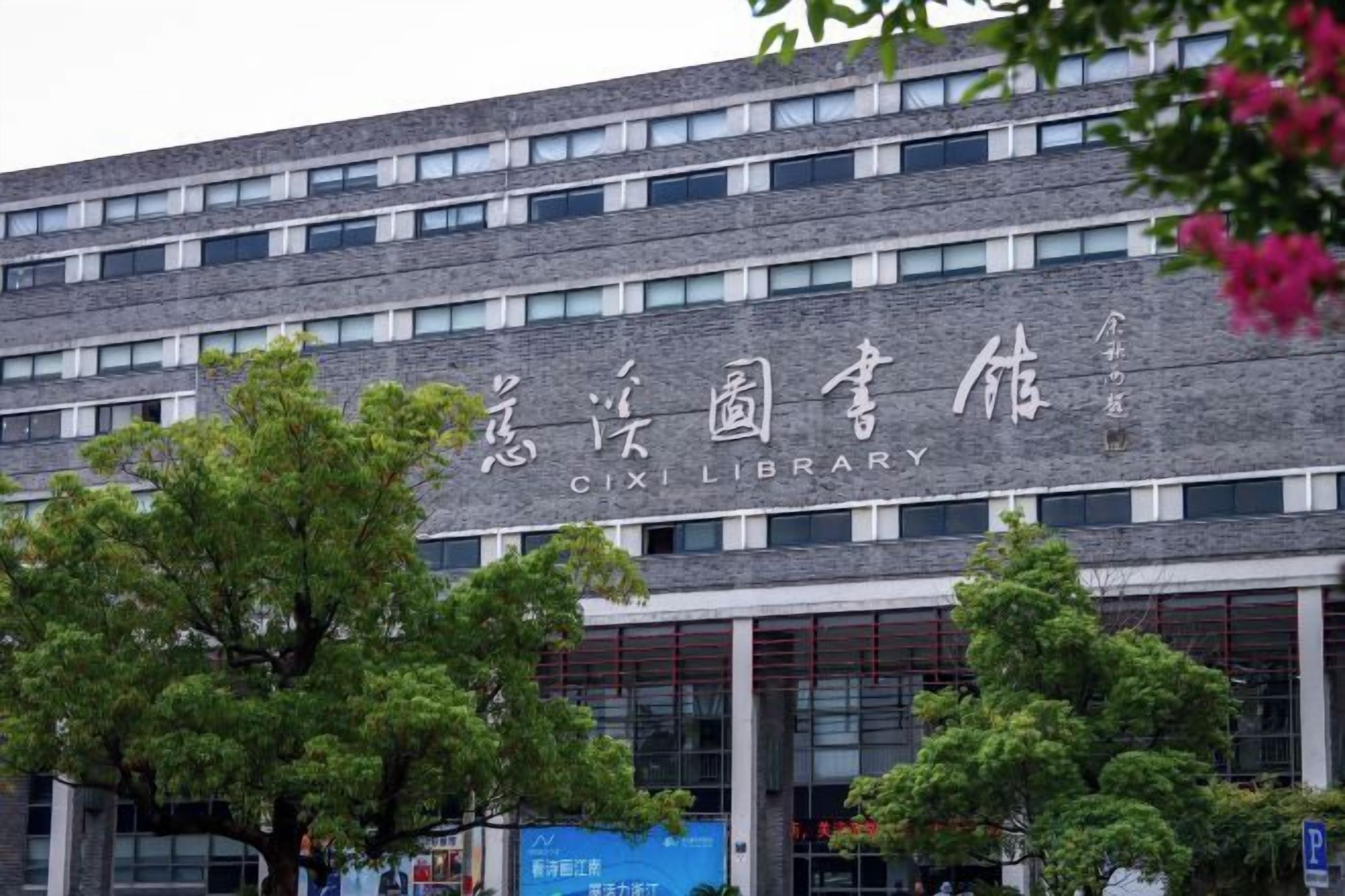 Un bâtiment sur lequel on peut lire, en anglais et en caractères chinois, l’inscription « Bibliothèque de Cixi ».