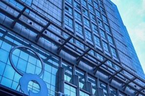 Un bâtiment moderne doté d’une façade en verre et d’un logo circulaire bien visible.