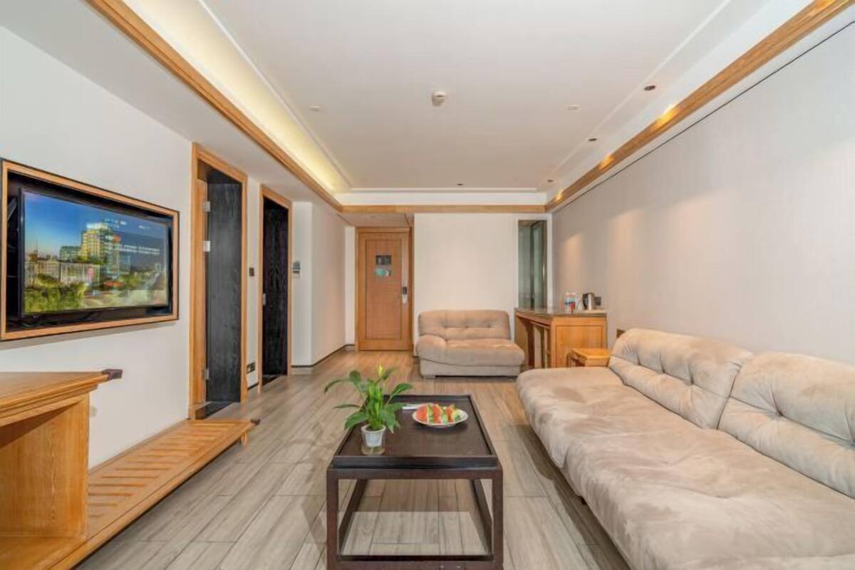 Een moderne woonkamer met een bank, een salontafel, een televisie en een deur naar een andere kamer.