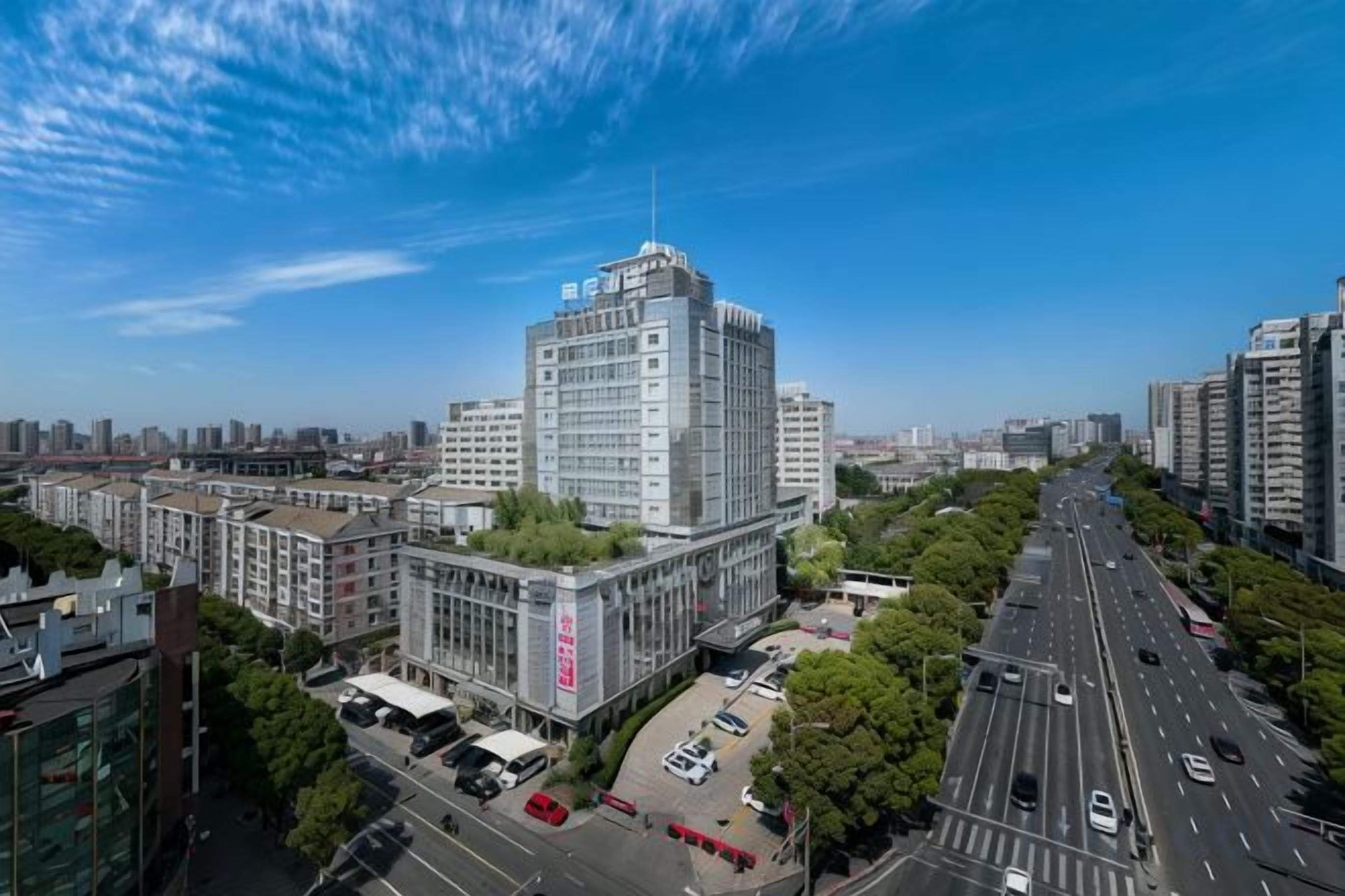 Un edificio de gran altura con una entrada destacada, rodeado de otros edificios y una avenida con varios carriles.