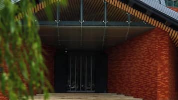 L'ingresso di un edificio con facciata in mattoni, tetto in metallo e una scalinata che conduce alla porta.