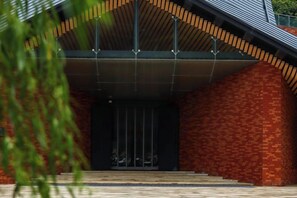 L’entrée d’un immeuble avec une façade en briques, un toit en métal et un escalier menant à la porte.