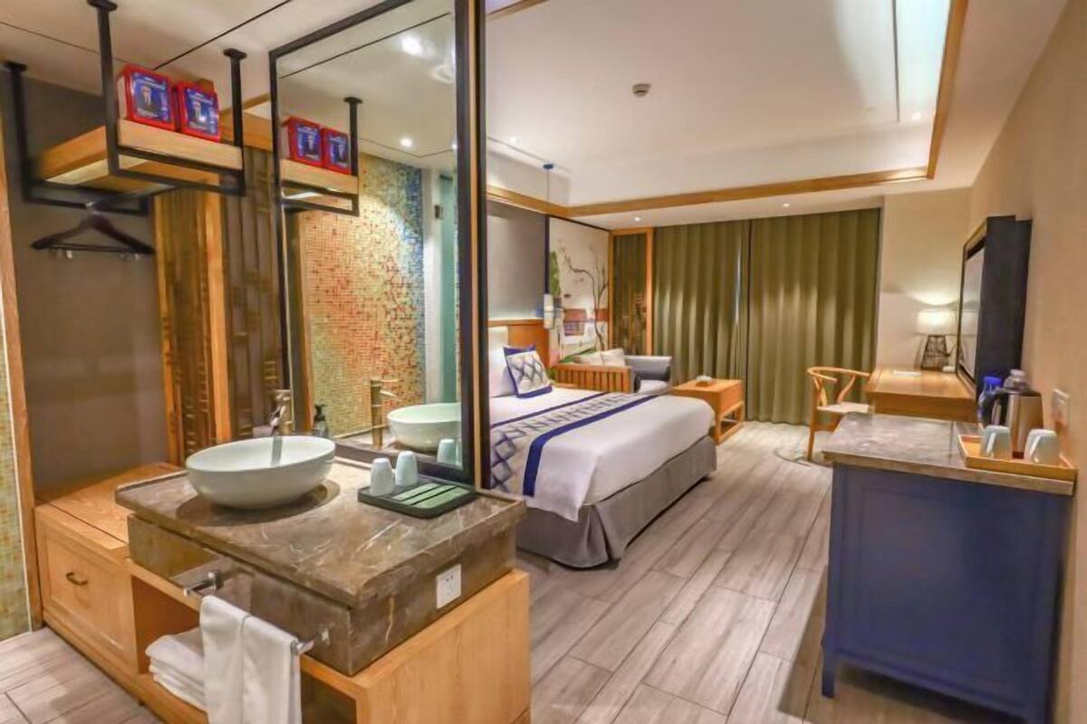 Een hotelkamer met een groot bed, een badkamer met een wastafel en spiegel, een bureau en een televisie.