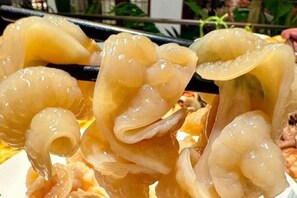 Primer plano de alimentos gelatinosos y translúcidos sostenidos con palillos.