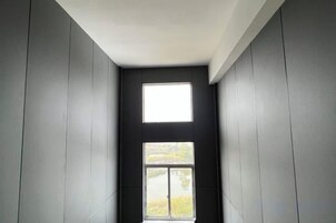 Una habitación estrecha con ventana y puerta.