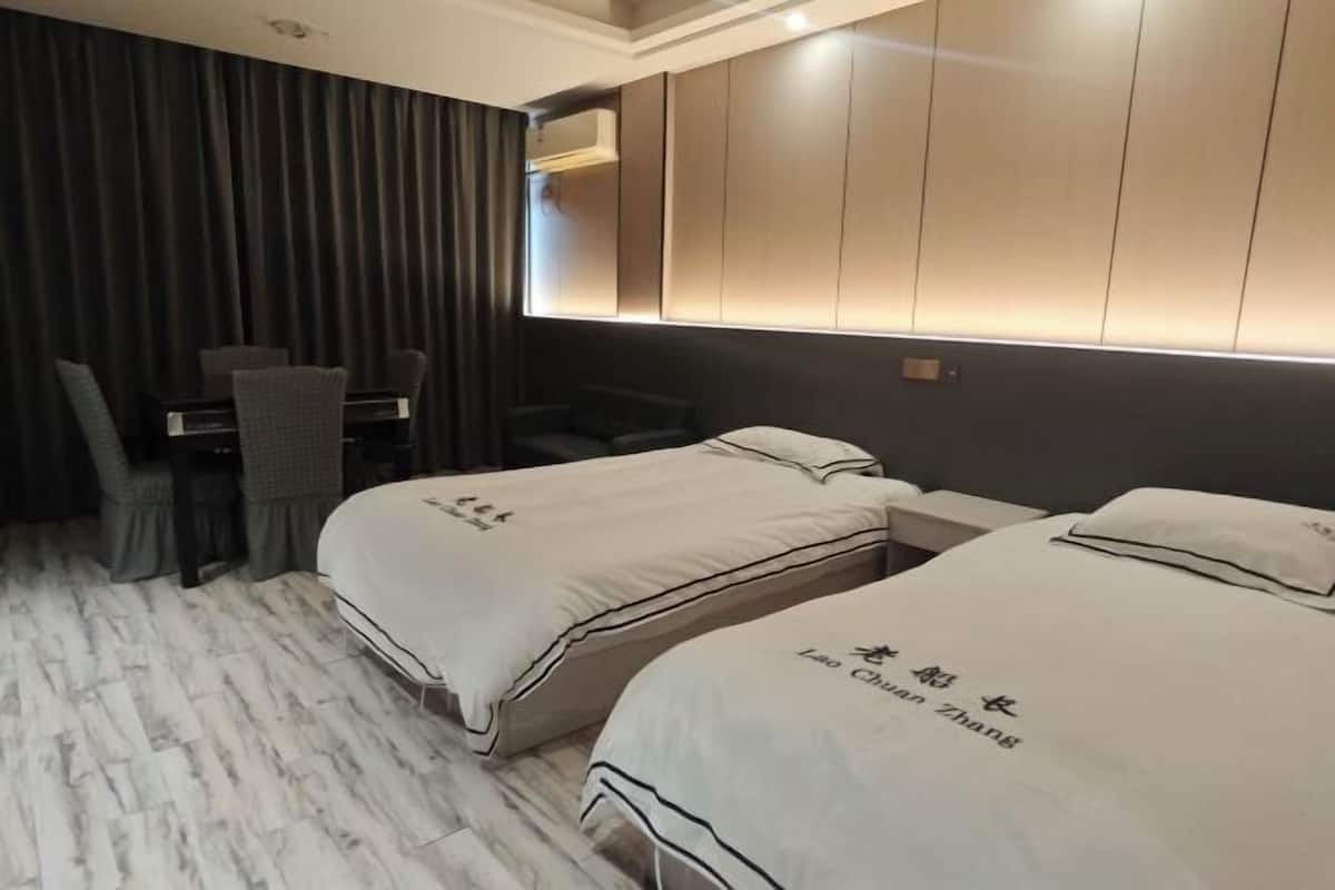 Een hotelkamer met twee bedden, een bureau en een stoel.