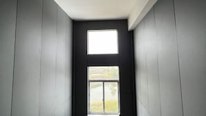 A narrow hallway with a window at the end, leading to a view of a lake and trees.