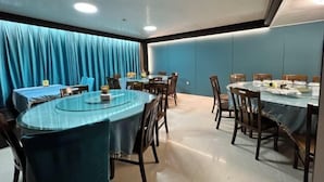 A conference room with round tables and chairs, blue curtains, and recessed lighting.