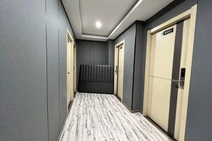 Un pasillo con piso estampado, un banco acolchado y puertas con un letrero.