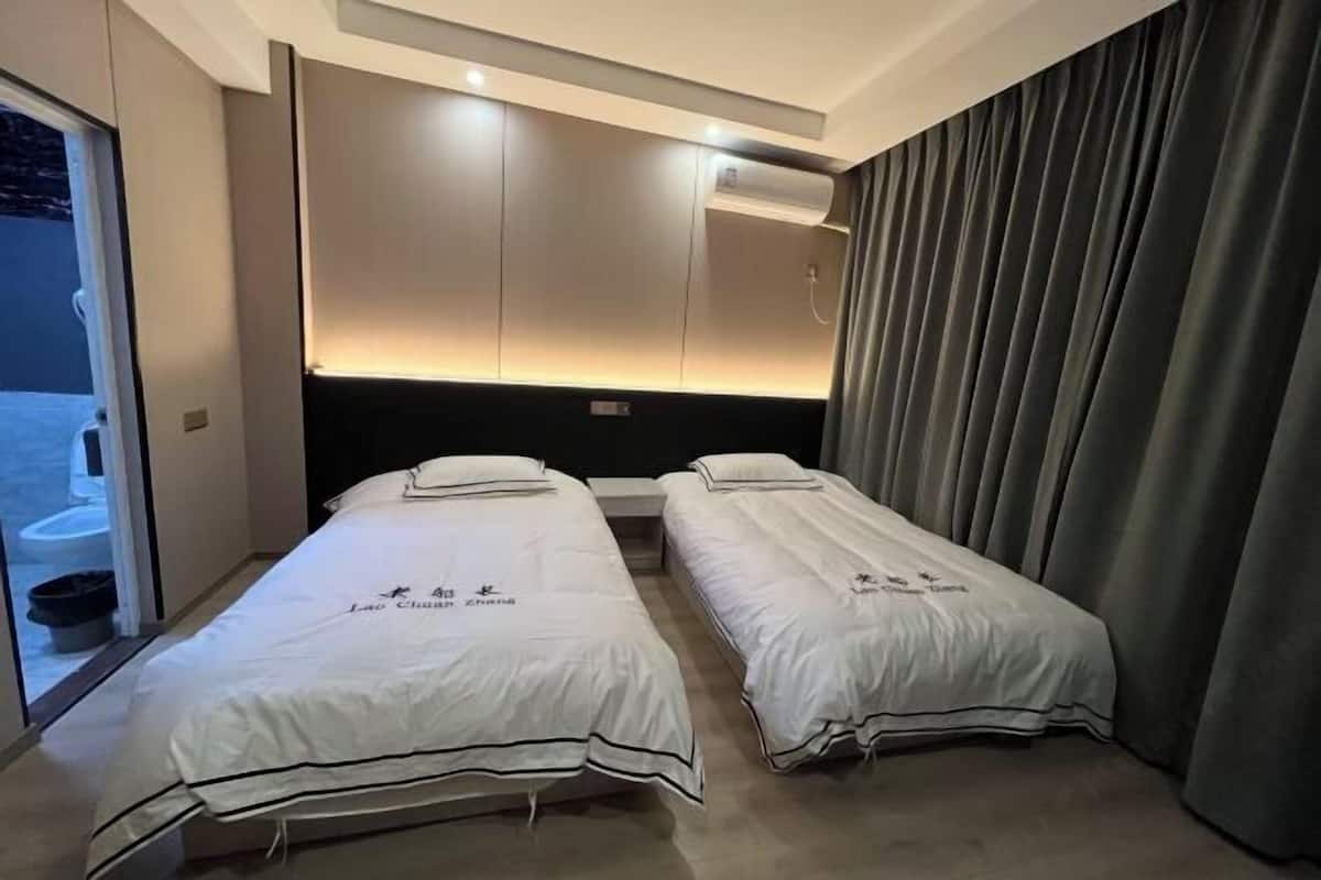Een hotelkamer met twee bedden, een schuifdeur links en een gordijn rechts.