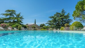 A clear swimming pool with lounge chairs and a building in the background. - Cottage with pool in Provence N°2 (La Roque-sur-Pernes)
