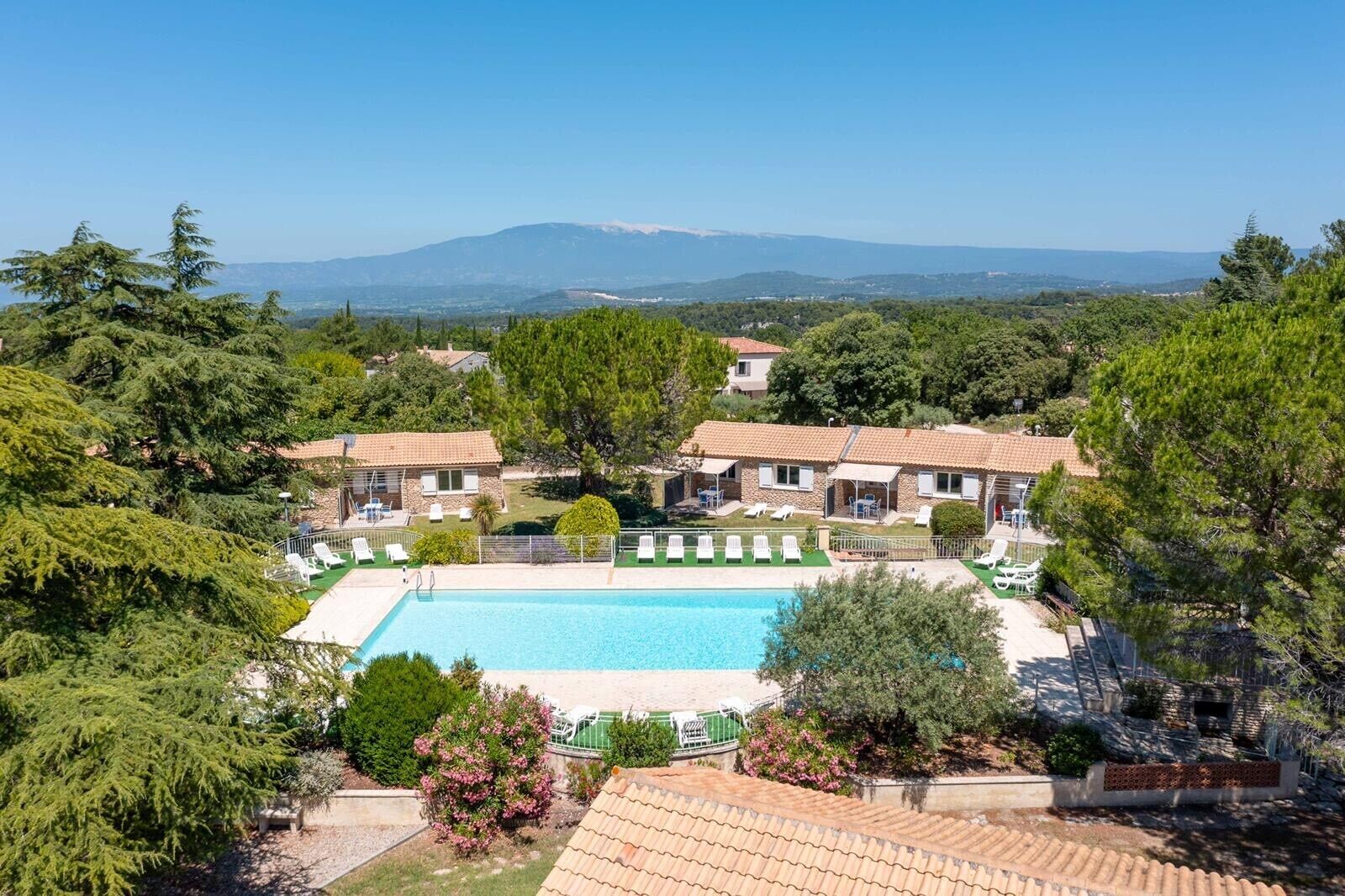 Uma villa com piscina, rodeada por vegetação exuberante e vista para as montanhas.