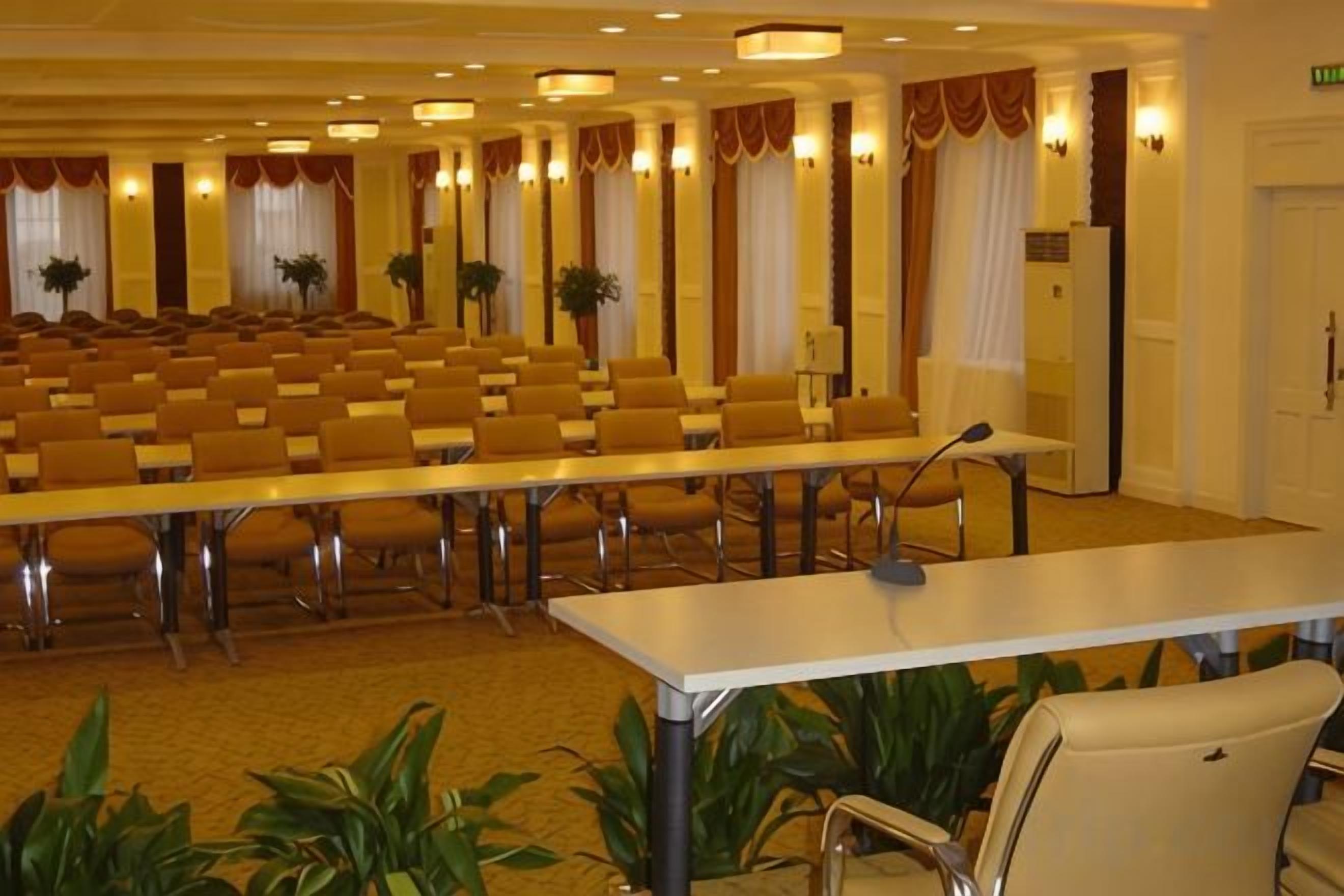 A conference room with rows of chairs, a long table, and a microphone.