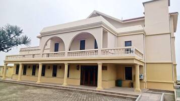 A two-story building with a balcony, a covered walkway, and a large entrance door.