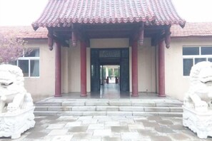 A traditional building with a tiled roof, a central entrance, and two stone lion statues. - Qingdao Tianheng Island Homestay (Qingdao)