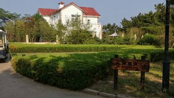 A building with a red roof, surrounded by well-maintained gardens and a signboard.